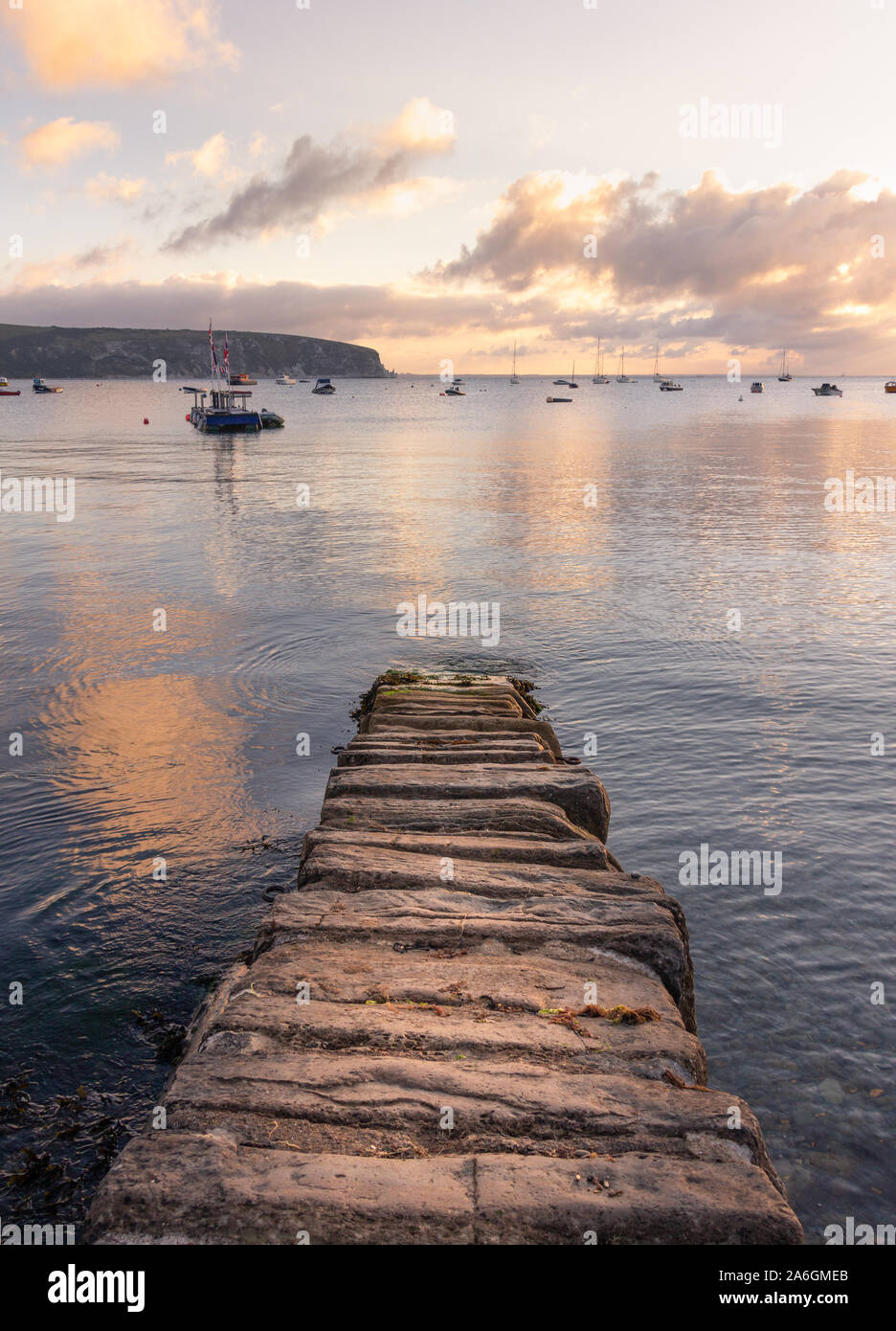 Coastal sunrise casts dawn light on stone jetty Stock Photo