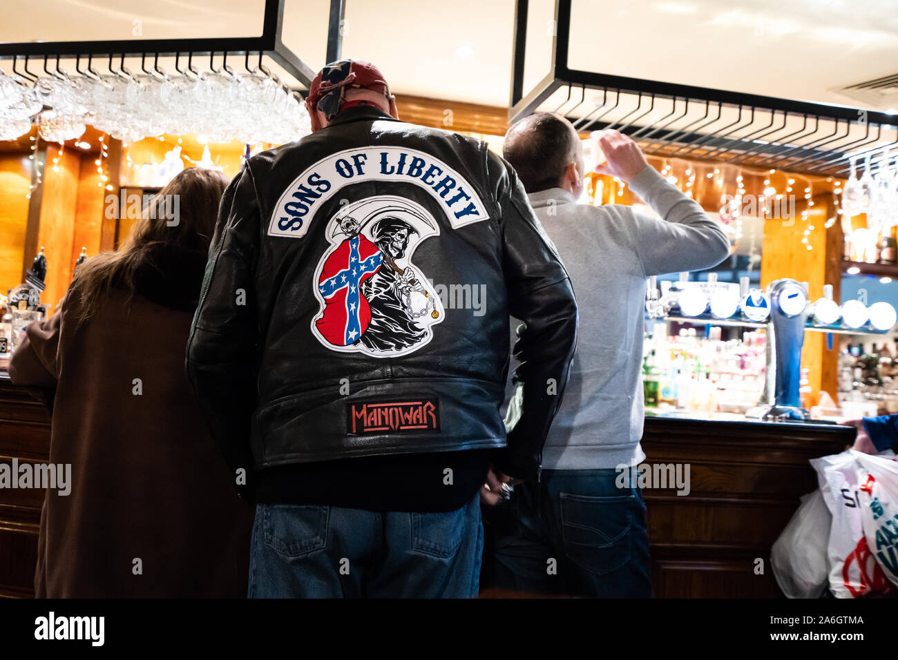 A man wearing a bikers jacket, gang related clothing queuing at the bar of the Reginald Mitchell, Wetherspoons public house Stock Photo