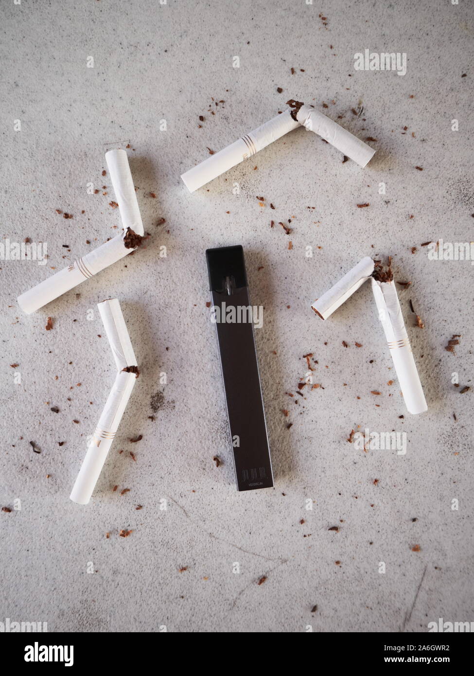 Vape device electronic cigarette juul, as smoking alternative with broken marlboro gold cigarettes and scattered tobacco on white textured background Stock Photo