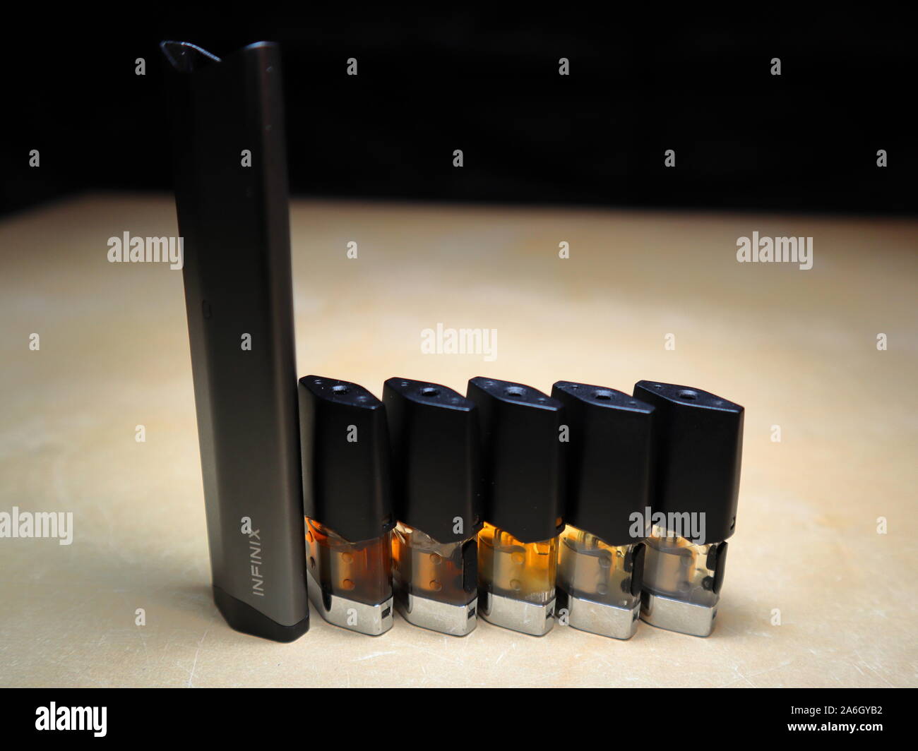 Smok Infinix refillable pod vape pen electronic cigarette with pods filled with e-juices of different shades of orange arranged in a gradient, isolate Stock Photo
