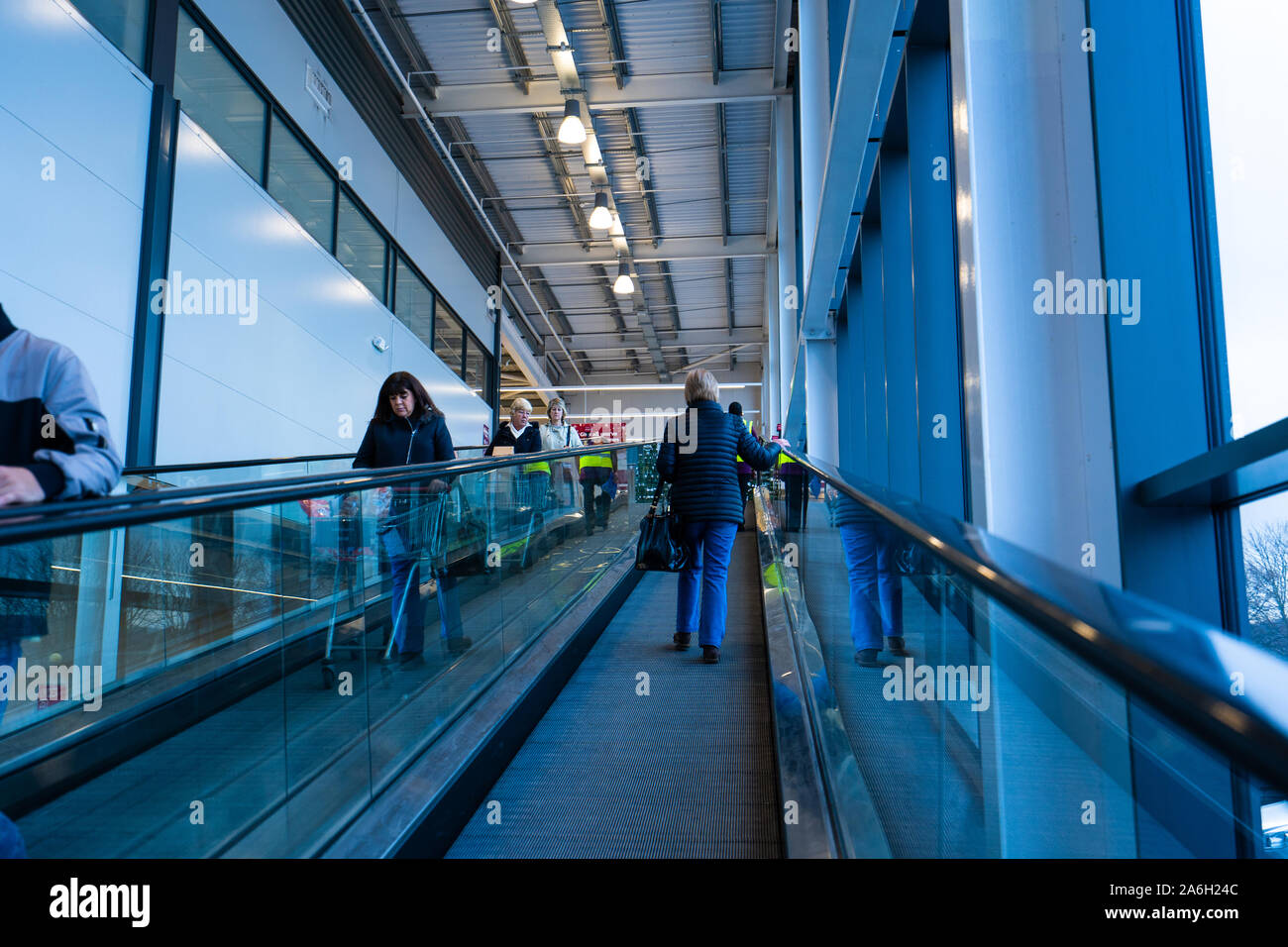 People ride the escalator at the large Sainsbury's store, shop
