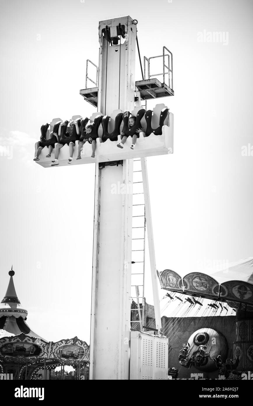 A group of visitors enjoy rides on the rollercoasters, dodgems and other fun rides and attractions at pleasureland, pleasure land in Wales Stock Photo