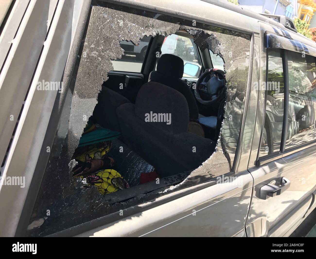closeup broken car window, a large hole, and shattered glass looking