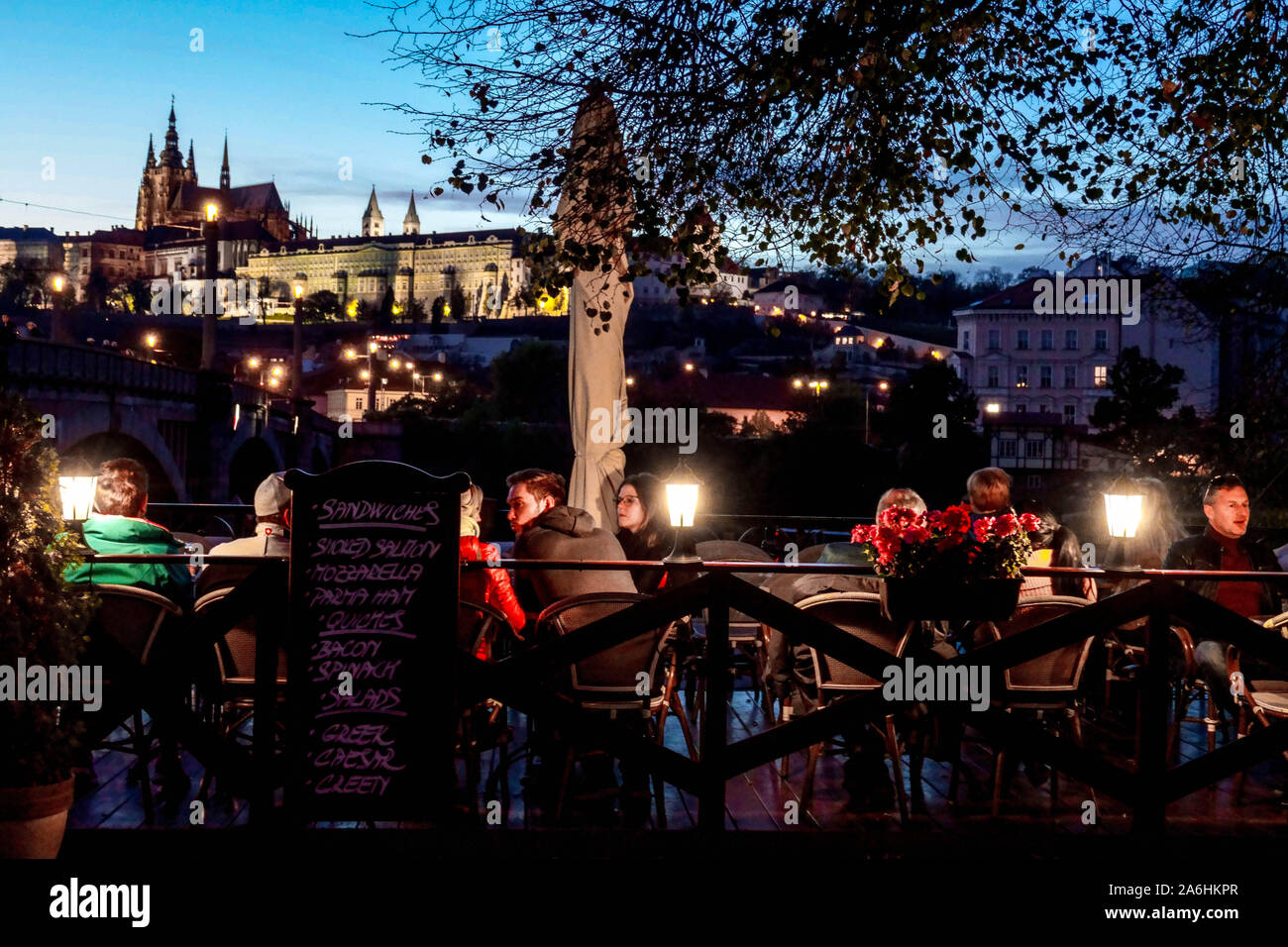 Prague People in a riverside bar at Vltava River, Restaurant, Tourists overlooking the Prague Castle night Prague Castle View Evening Atmosphere Stock Photo