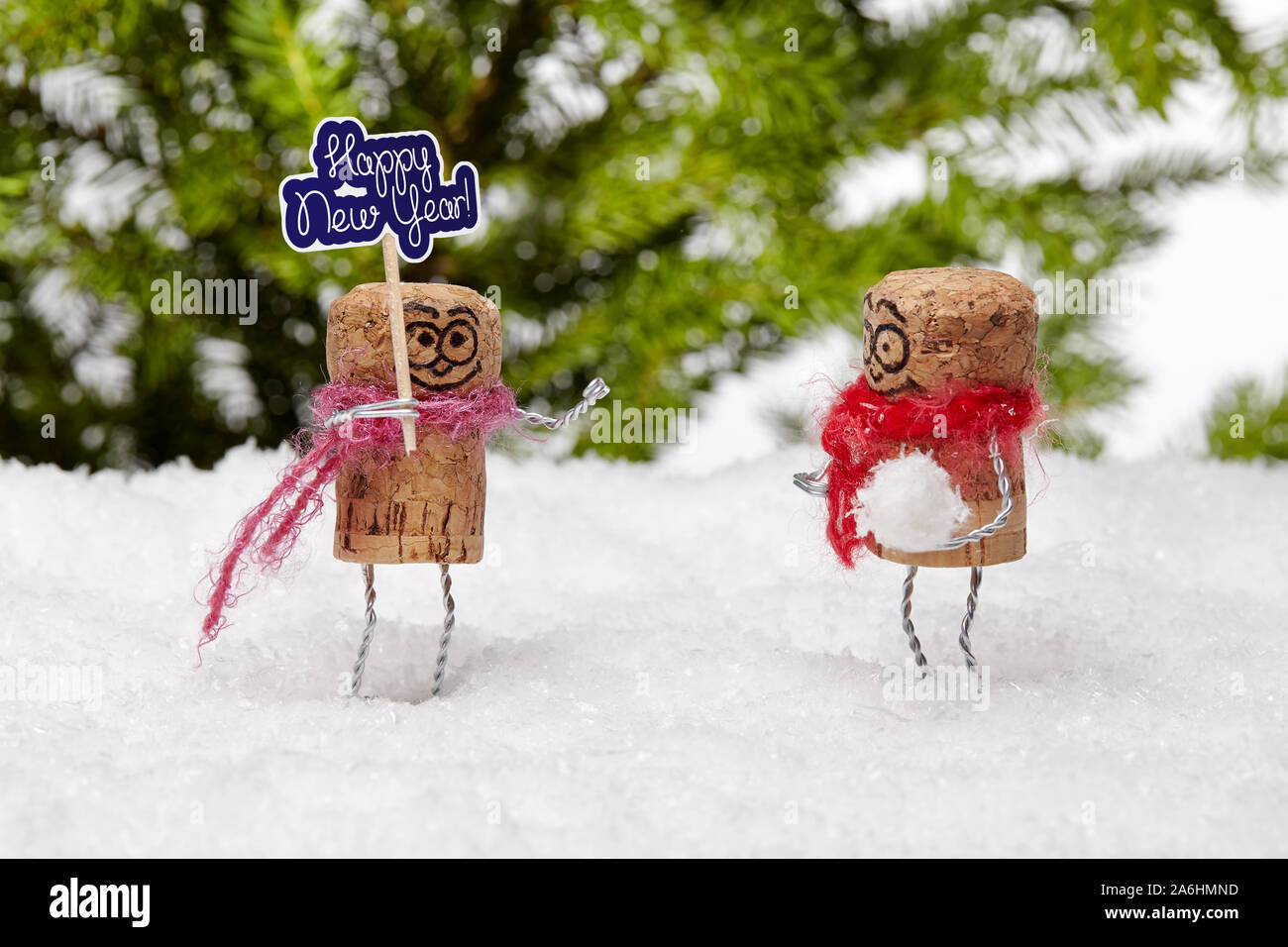 Funny champagne cork man on white snow wishes anybody 'happy new year', his playful pal wants to play snowball fight. Stock Photo
