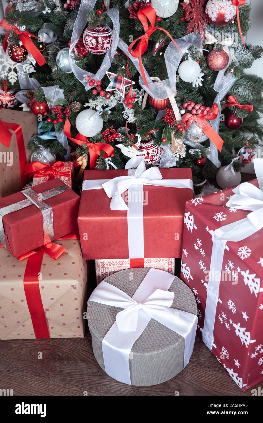 Boxes tied with ribbons under a Christmas tree in red colors. Symbol of ...