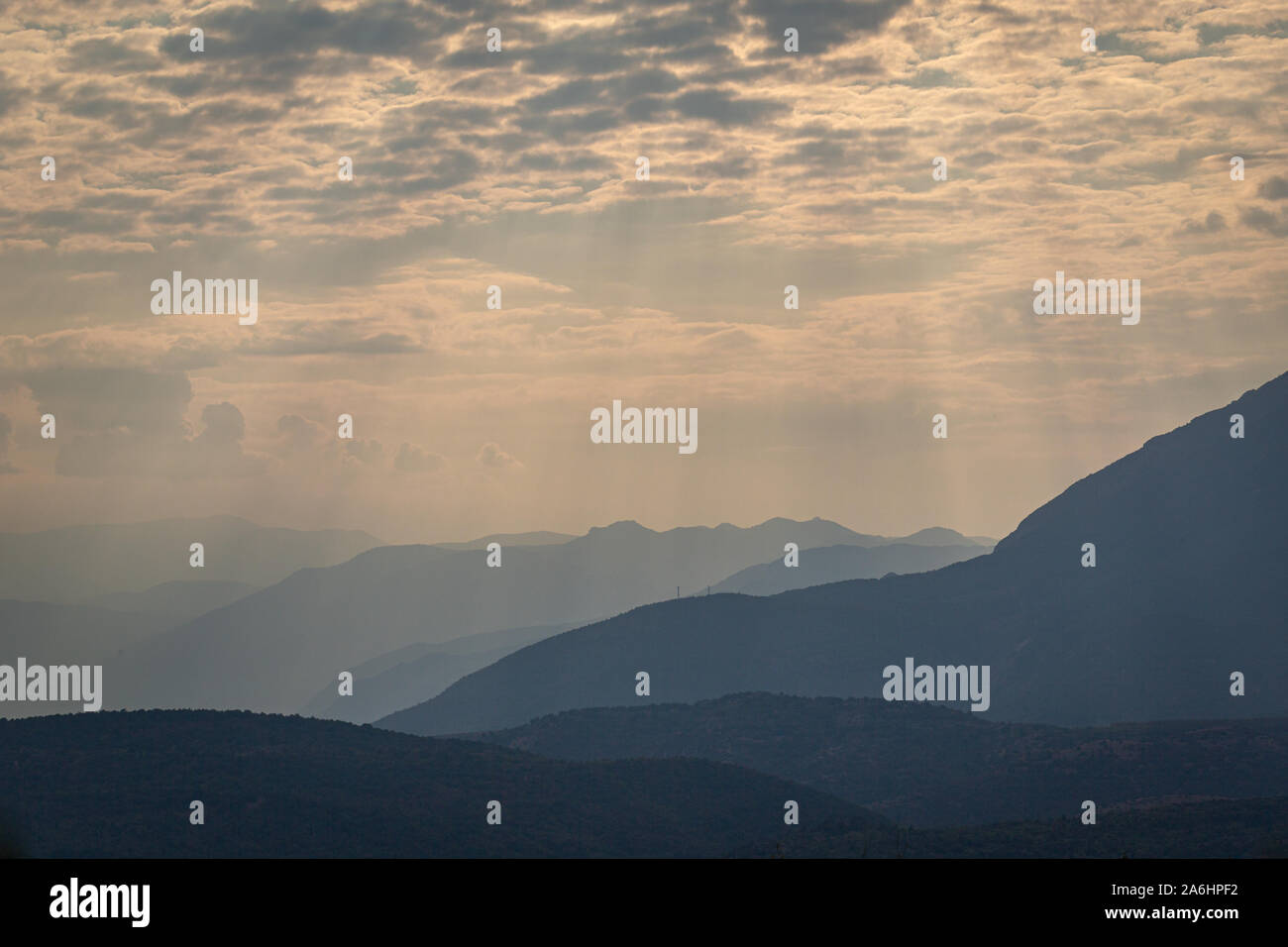 An unusually beautiful view of the mountains of Hellas illuminated by the rays of the sun, breaking through the holes from the clouds Stock Photo