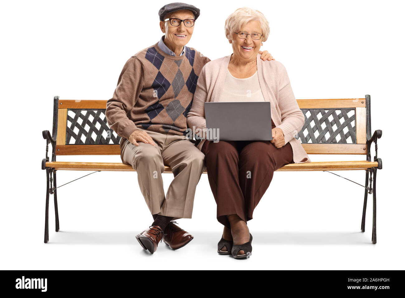 Senior couple on a bench with a laptop computer smiling at the camera isolated on white background Stock Photo