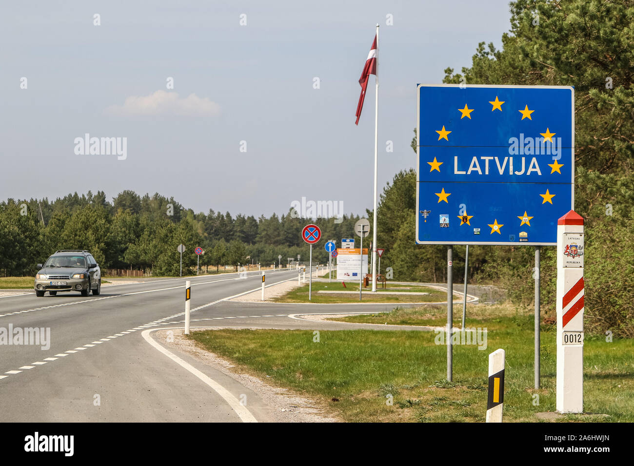 Latvia inscription on a sign with EU stars with with a Latvian flag in the  background is seen on a Lithuania - Latvia Schengen Area border crossing  Butinge (LT) - Rucava (LV)