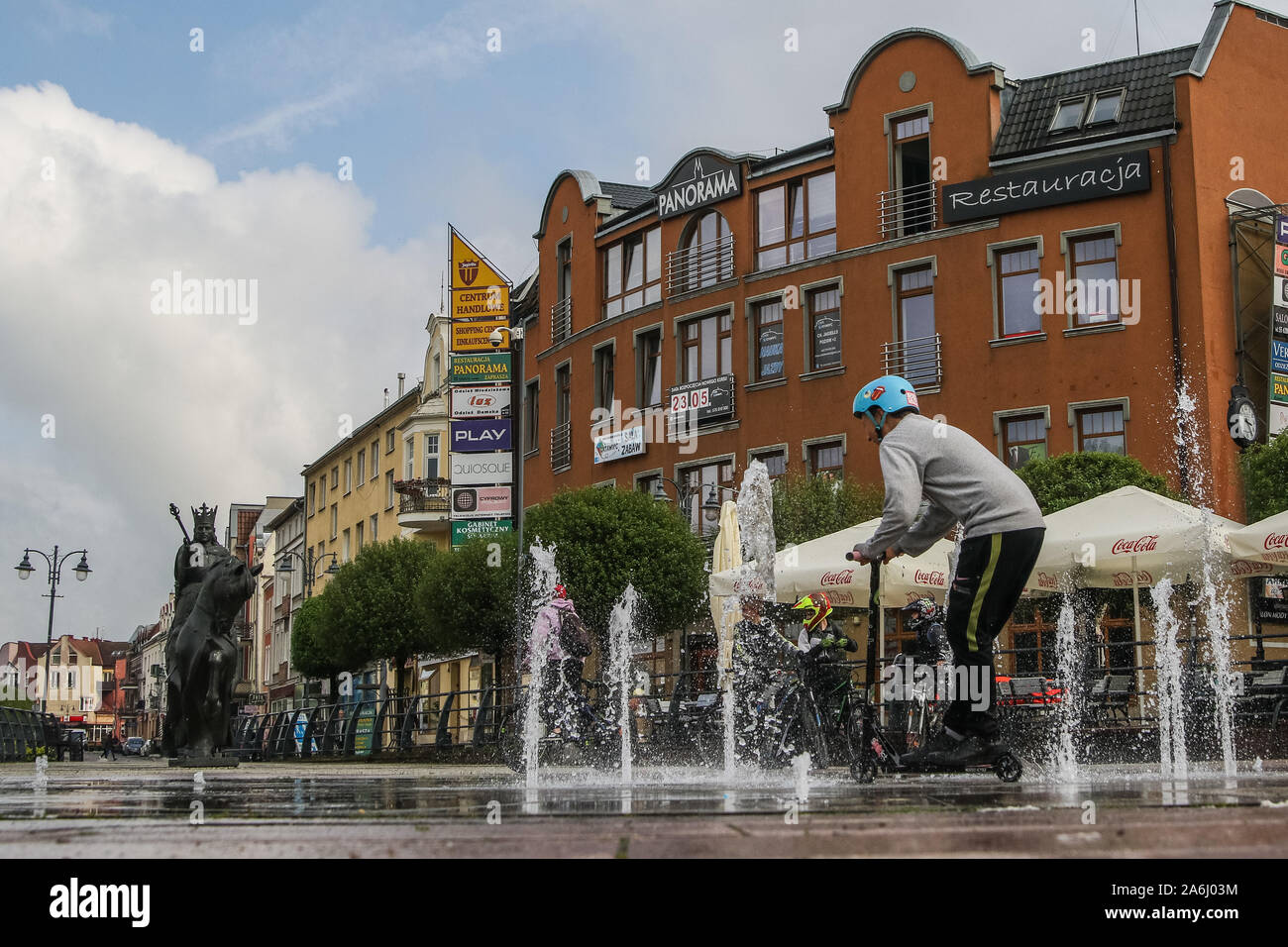 Children riding on bikes and scooters near the fountain in front of Casimir IV Jagiellon (Kazimierz Jagiellonczyk) monument are seen in the centre city of Malbork, Poland, on 18 May 2019  © Michal Fludra / Alamy Live News Stock Photo