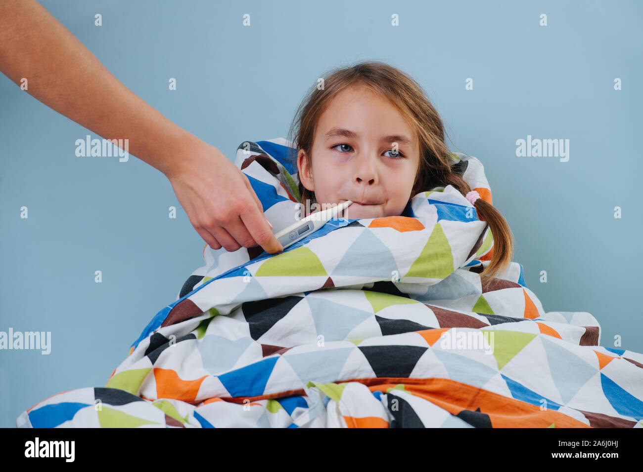 Sick little girl with common cold sitting in bed under blanket with thermometer Stock Photo Alamy