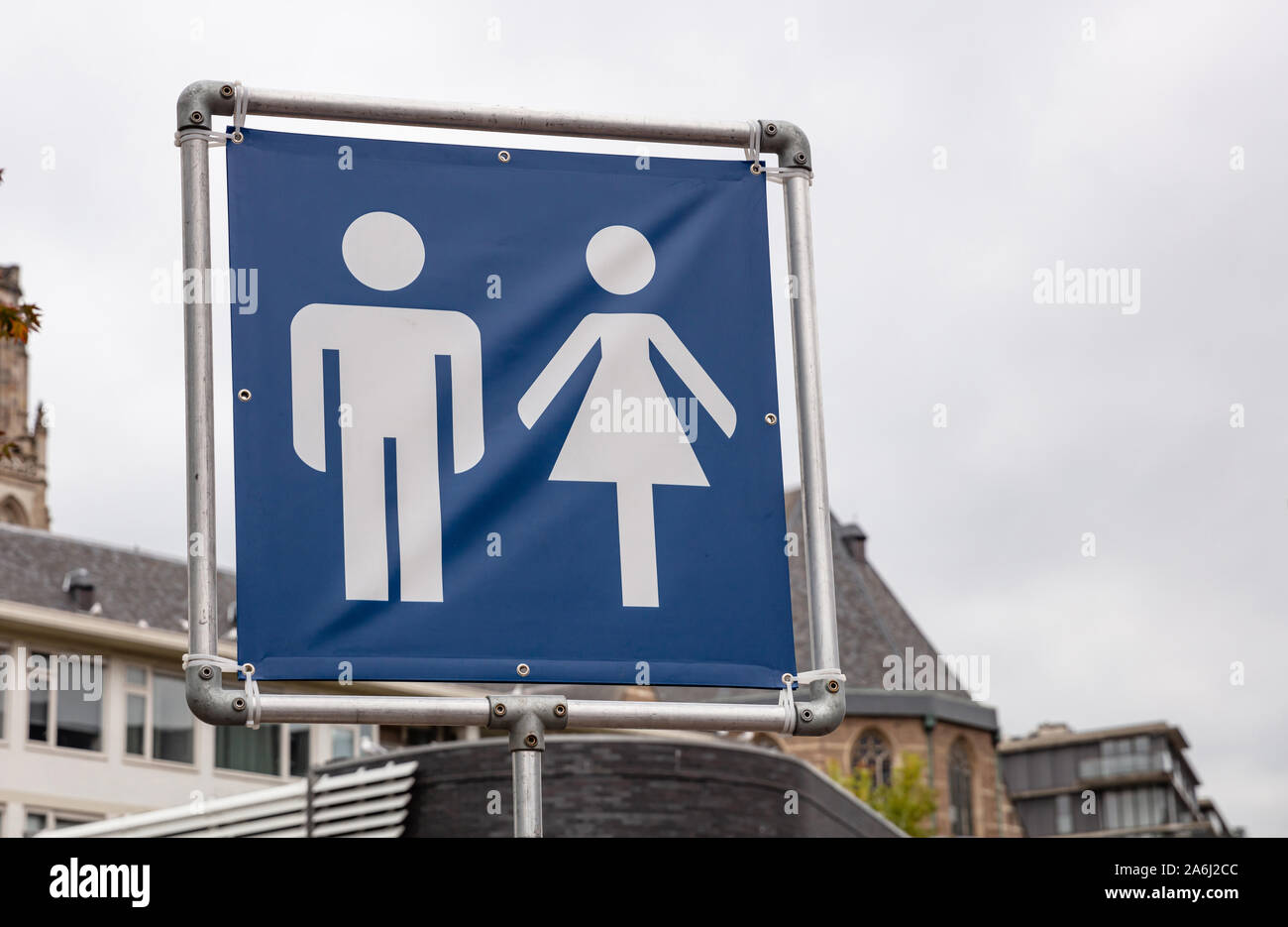 WC toilets sign. Mobile toilets signage in the city for an outdoors event, cloudy sky background. Square metal frame and blue fabric with human silhou Stock Photo