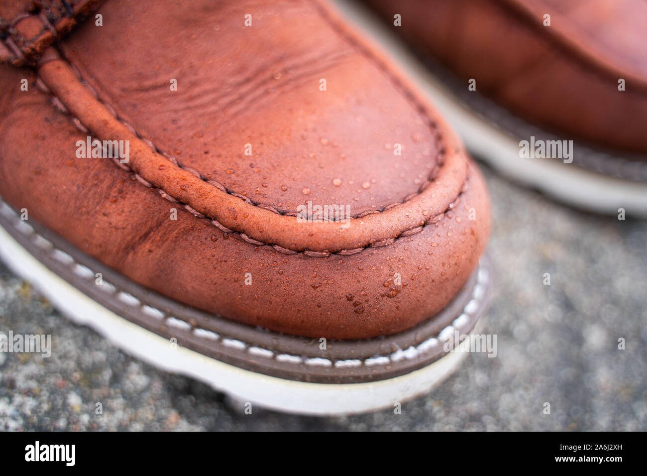 Water drops on red leather work boots close-up. The concept of water-repellent impregnation for leather shoes Stock Photo