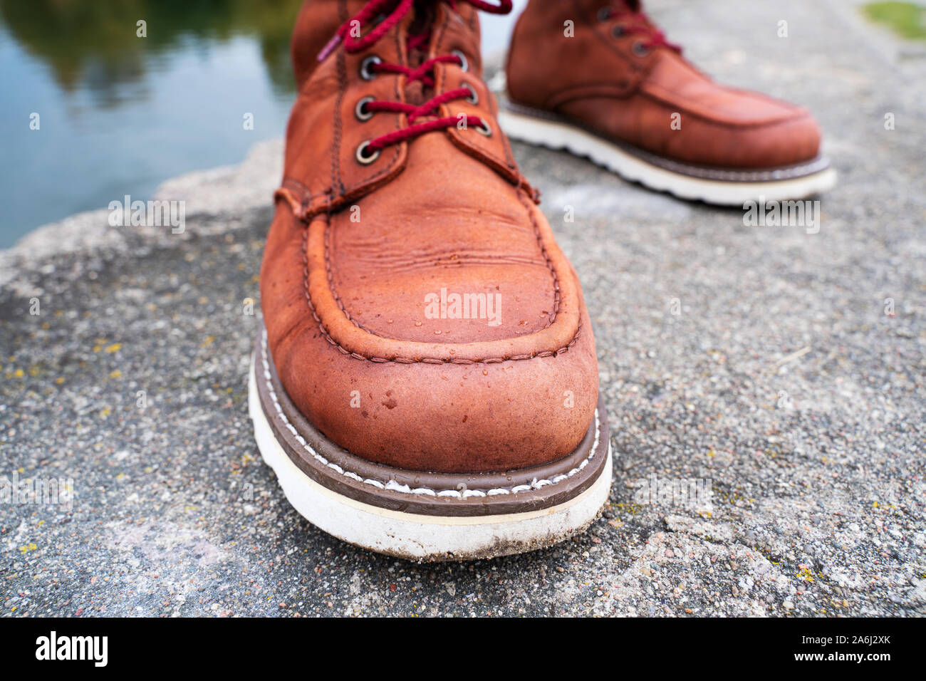 Water drops on red leather work boots close-up. The concept of water-repellent impregnation for leather shoes Stock Photo