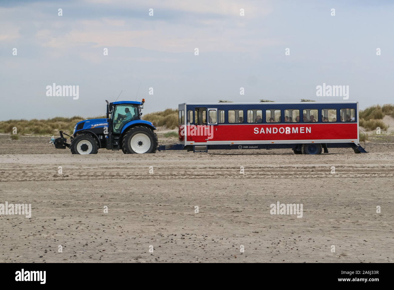 The Sandormen company tractor going with people by the beach to the Grenen the point where the North Sea and the Baltic sea collide is seen in Skagen, Denmark on 28 July 2019 People visit the place and stand with one leg in each sea, watching the waves arriving from each direction until, finally, they meet. © Michal Fludra / Alamy Live News Stock Photo