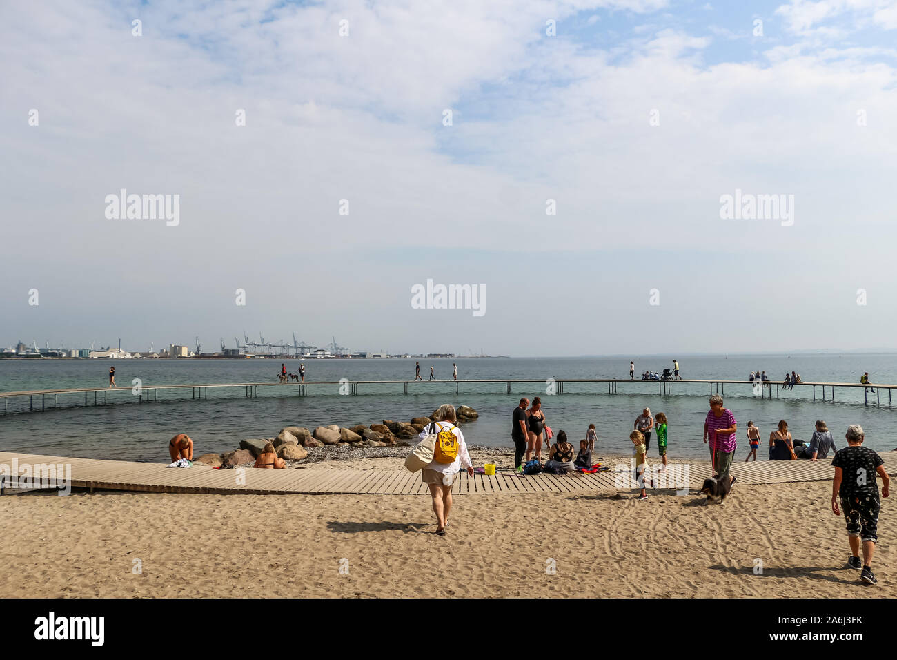 People walking by the The Infinite Bridge (Den Uendelige Bro) - circle shaped wooden pier built on a sea coast of a Aarhus Bay on a Varna Beach/Ballehage Beach, created by architect Niels Povlsgaard and Johan Gjødes are seen in Aarhus, Denmark on 30 July 2019 © Michal Fludra / Alamy Live News Stock Photo