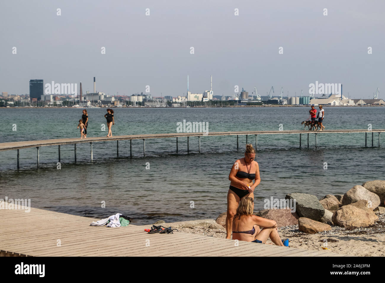 People walking by the The Infinite Bridge (Den Uendelige Bro) - circle shaped wooden pier built on a sea coast of a Aarhus Bay on a Varna Beach/Ballehage Beach, created by architect Niels Povlsgaard and Johan Gjødes are seen in Aarhus, Denmark on 30 July 2019 © Michal Fludra / Alamy Live News Stock Photo