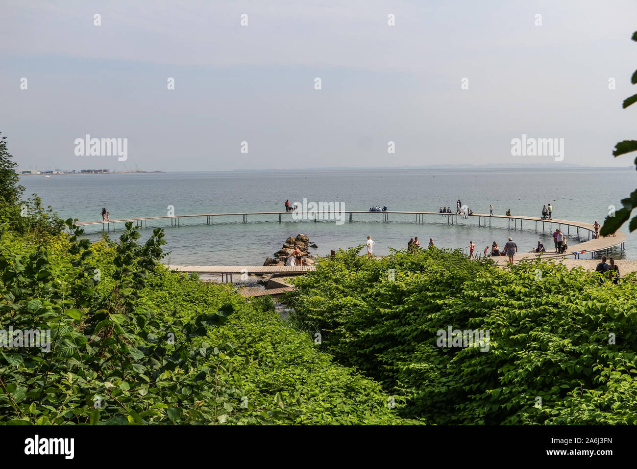 People walking by the The Infinite Bridge (Den Uendelige Bro) - circle shaped wooden pier built on a sea coast of a Aarhus Bay on a Varna Beach/Ballehage Beach, created by architect Niels Povlsgaard and Johan Gjødes  are seen in Aarhus, Denmark on 30 July 2019  © Michal Fludra / Alamy Live News Stock Photo