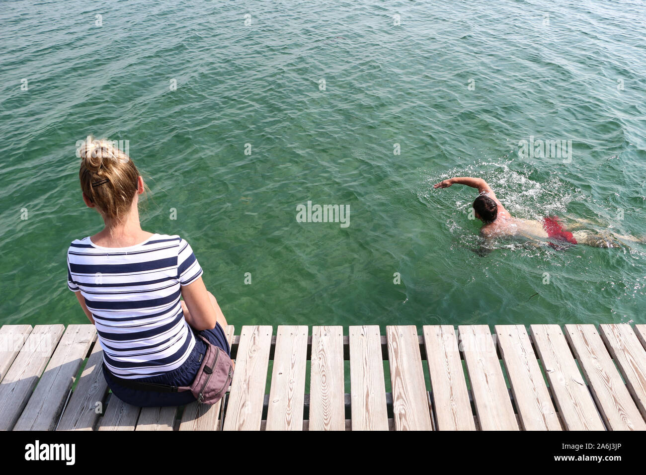 Man swimming around the Infinite Bridge (Den Uendelige Bro) - circle shaped wooden pier built on a sea coast of a Aarhus Bay on a Varna Beach/Ballehage Beach, created by architect Niels Povlsgaard and Johan Gj¿des are seen in Aarhus, Denmark on 30 July 2019 © Michal Fludra / Alamy Live News Stock Photo