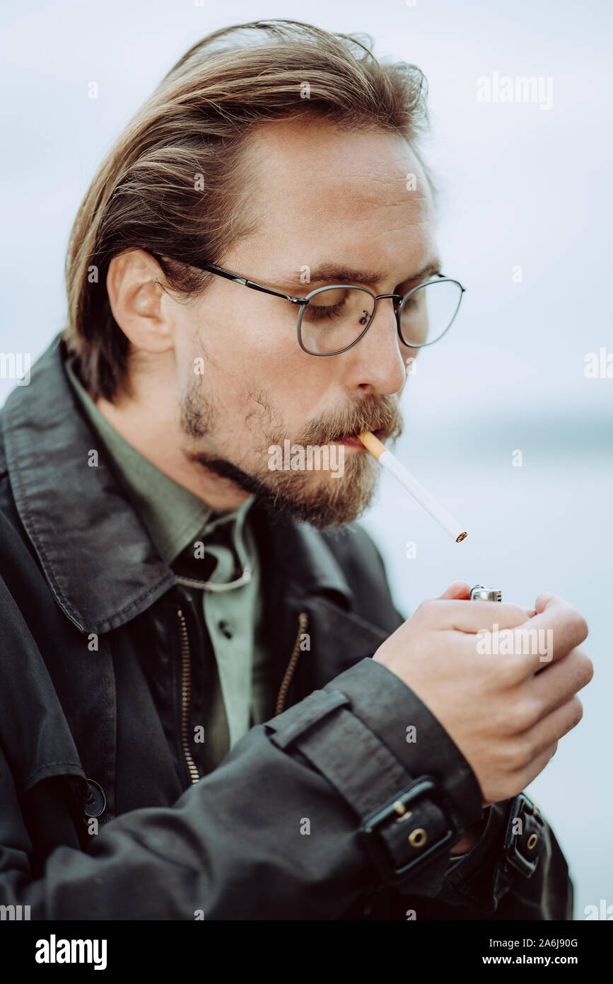 Photo of a young man lighting up a cigarrete Stock Photo