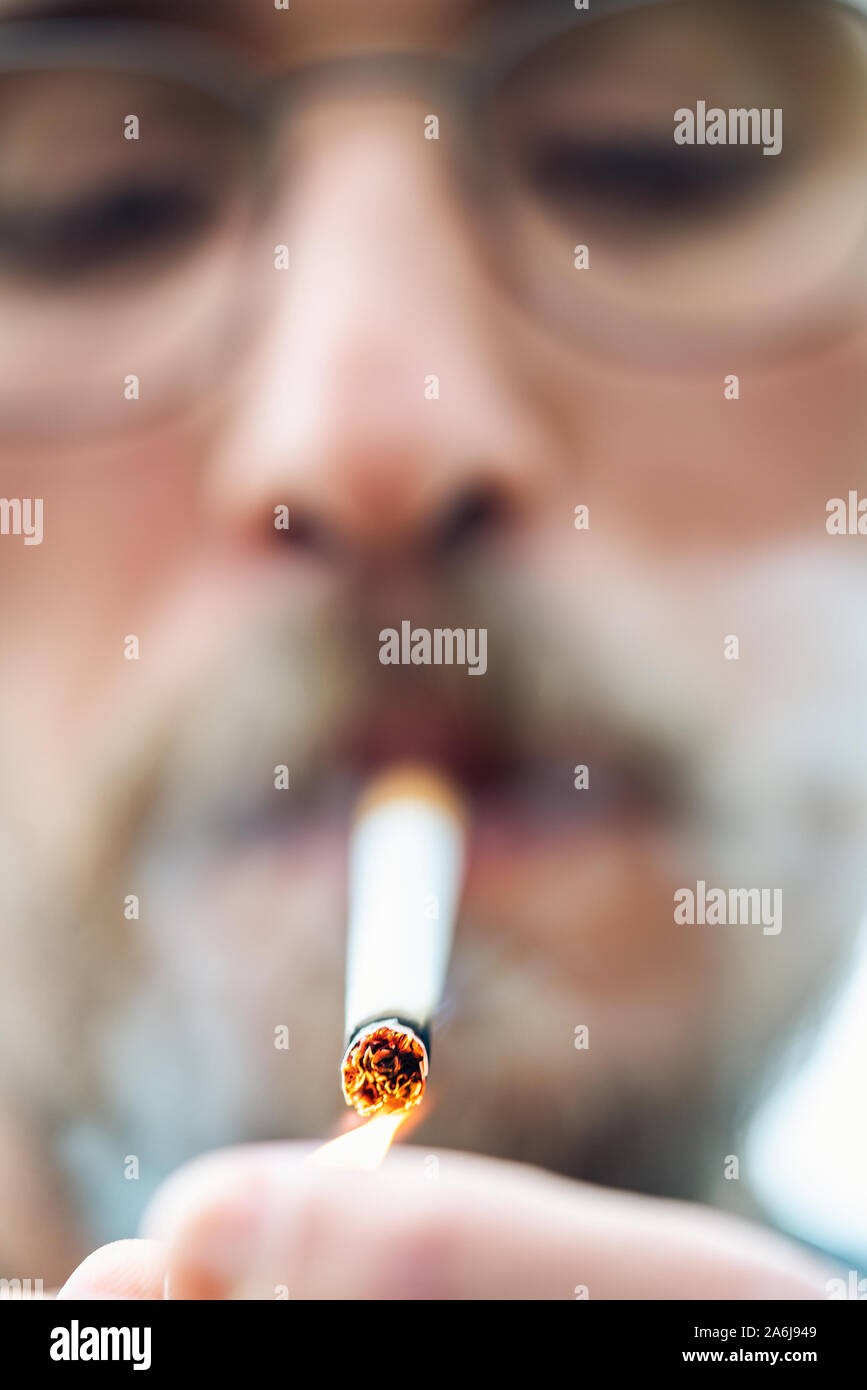 Close-up photo of a young man lighting up a cigarette Stock Photo