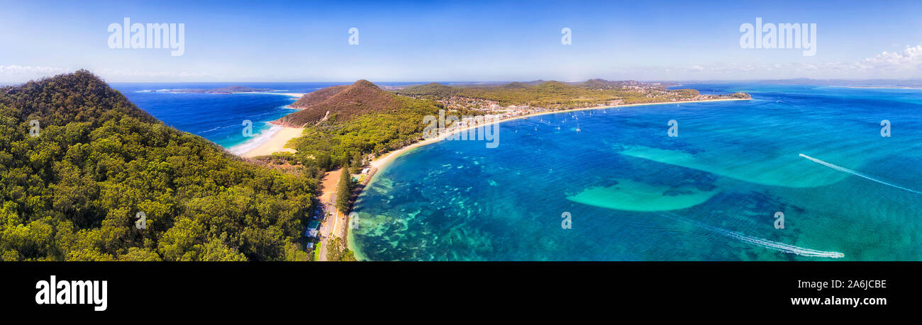 Port Stephens coast Shoal bay town waterfront with Mt Tomaree and Zenith beach in wide aerial panorama over water surface in Australia on a sunny day. Stock Photo