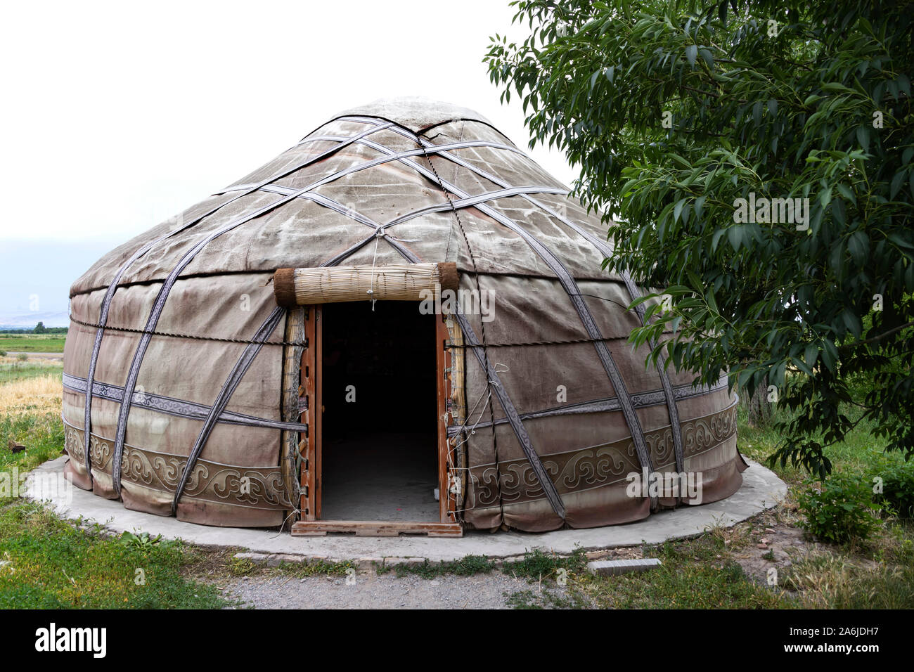 White yurt with an open entrance next to a tree. Kyrgyzstan Stock Photo
