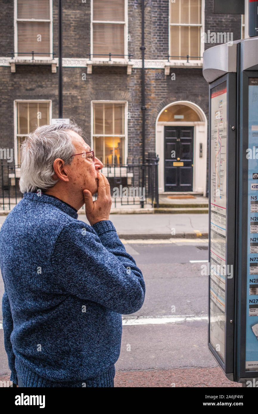 middle-aged man looking at bus time table at bus stop Stock Photo