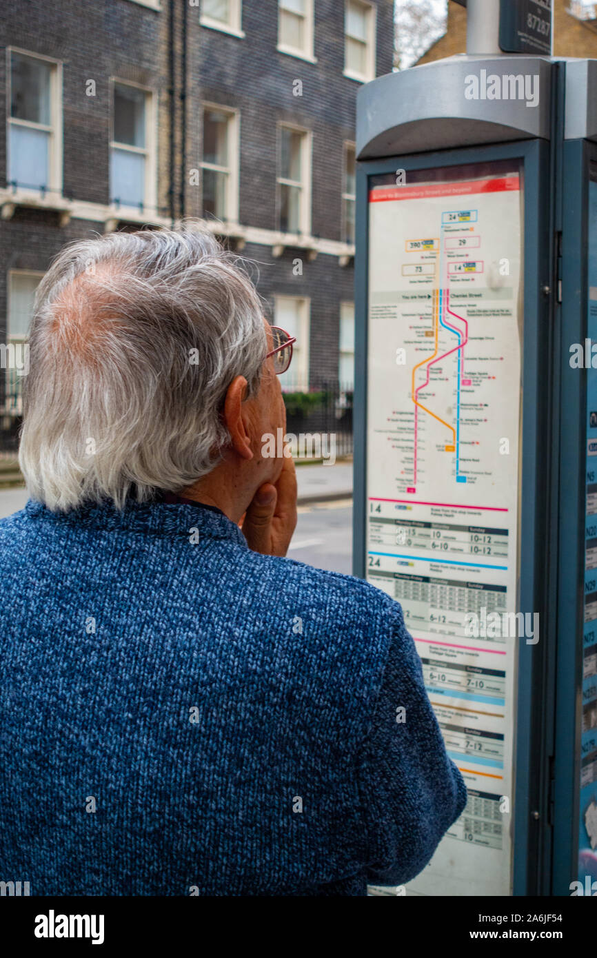 middle-aged man looking at bus time table at bus stop Stock Photo