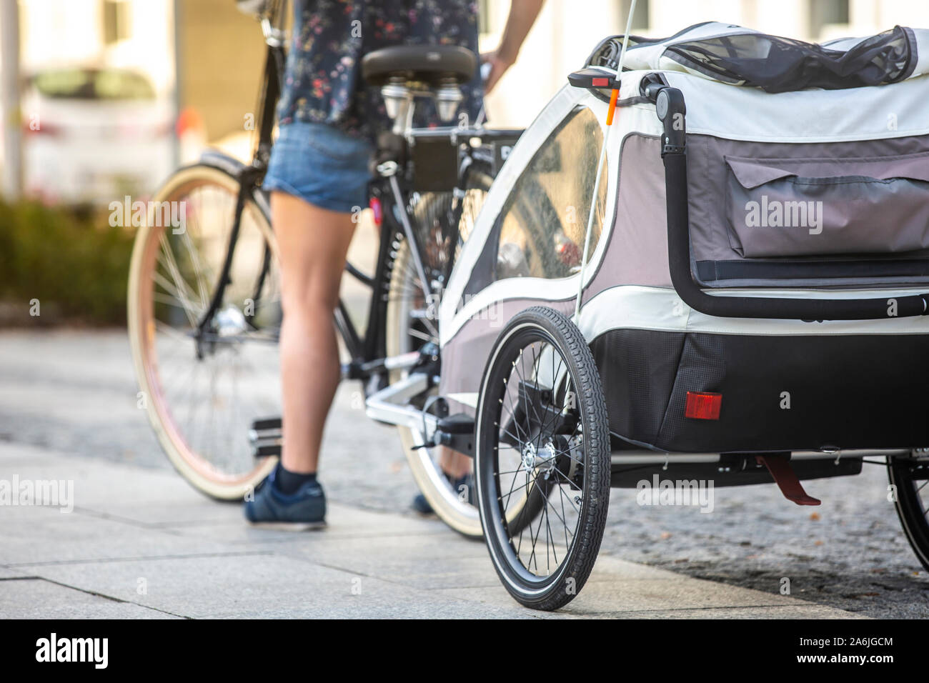 An unidentified woman riding a bicycle with a baby stroller attached to the bicycle Stock Photo Alamy