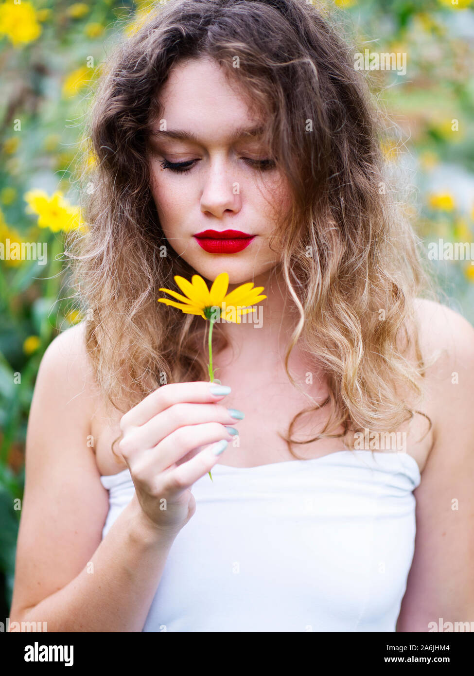 Beautiful young woman holding yellow flower Stock Photo