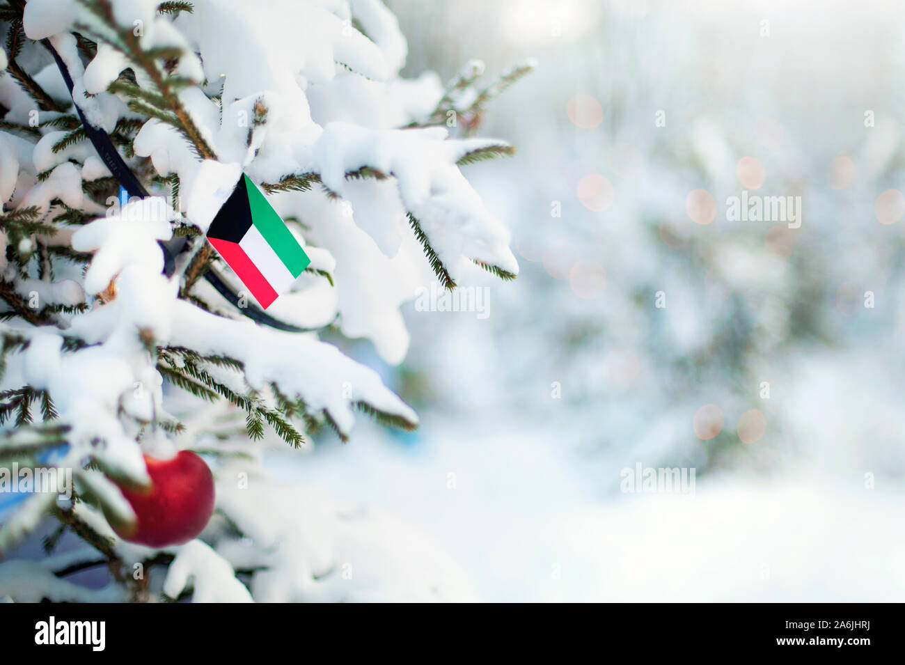 Christmas Kuwait. Xmas tree covered with snow, decorations and a flag