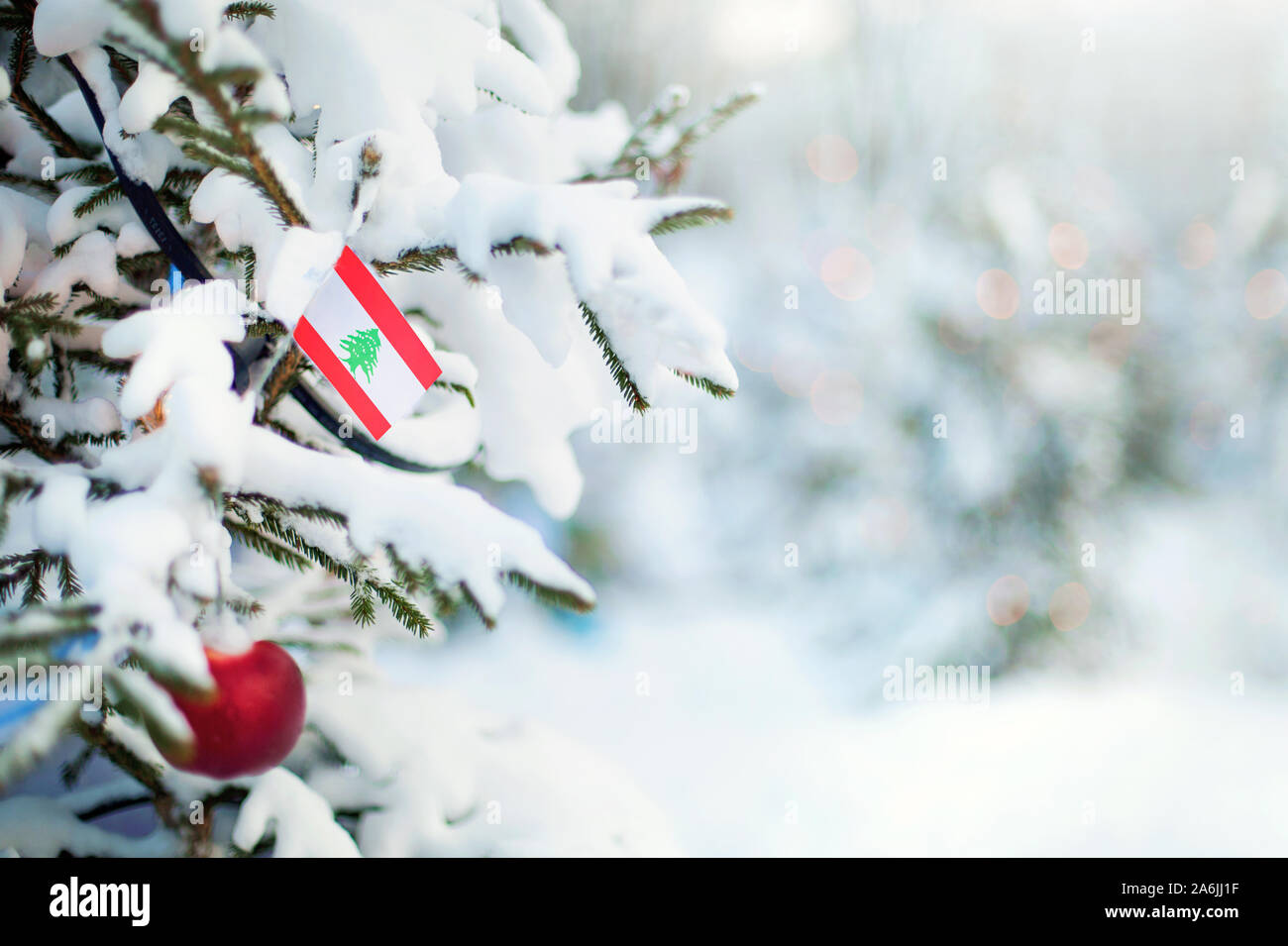 Christmas Lebanon. Xmas tree covered with snow, decorations and a flag