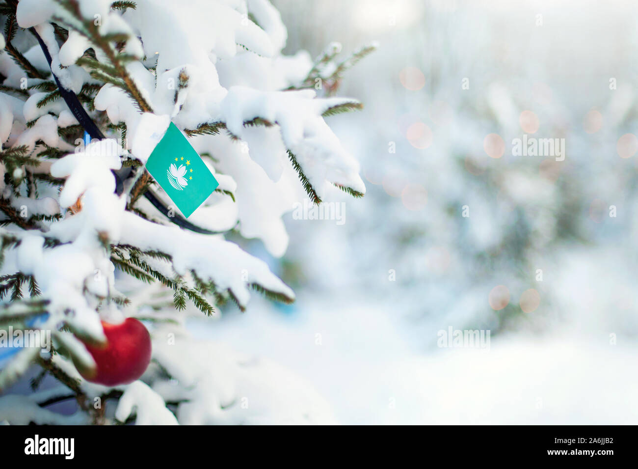 Christmas Macau. Xmas tree covered with snow, decorations and a flag ...