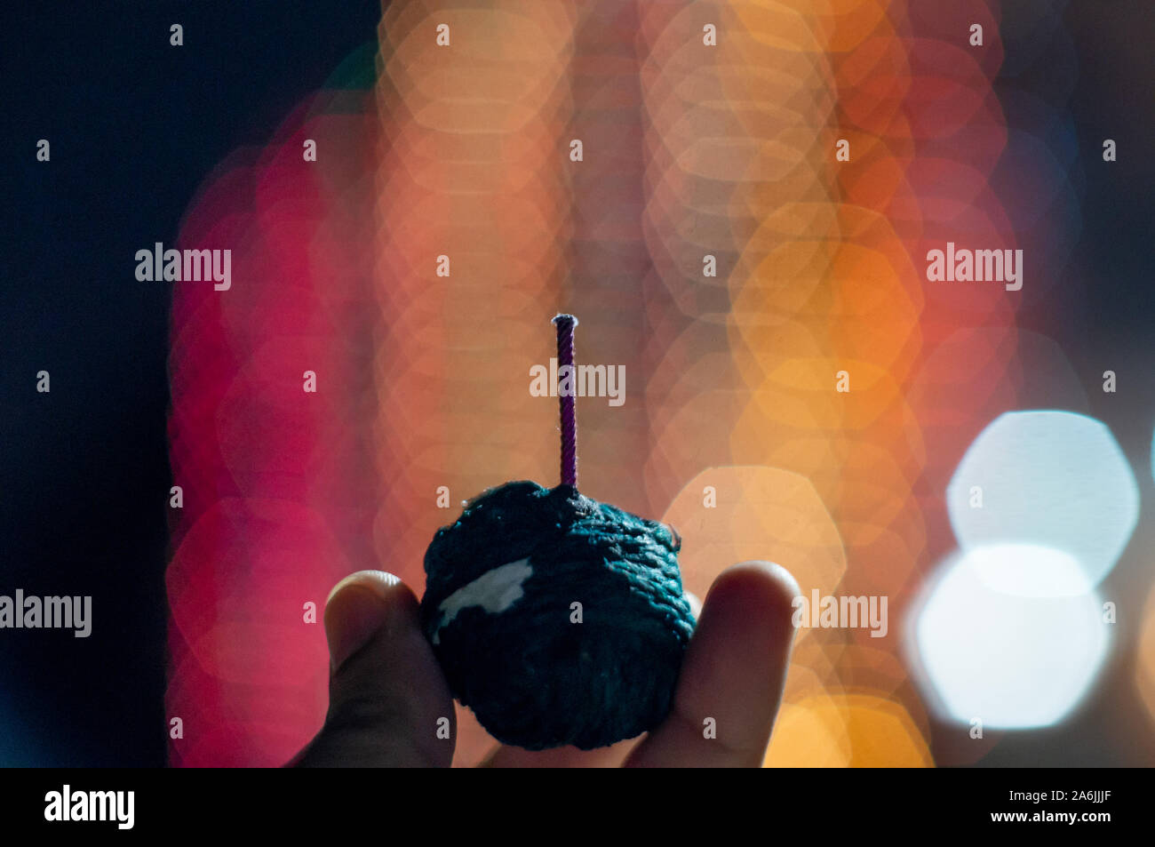 Human hand holding green sutli rassi bomb in front of out of focus ...