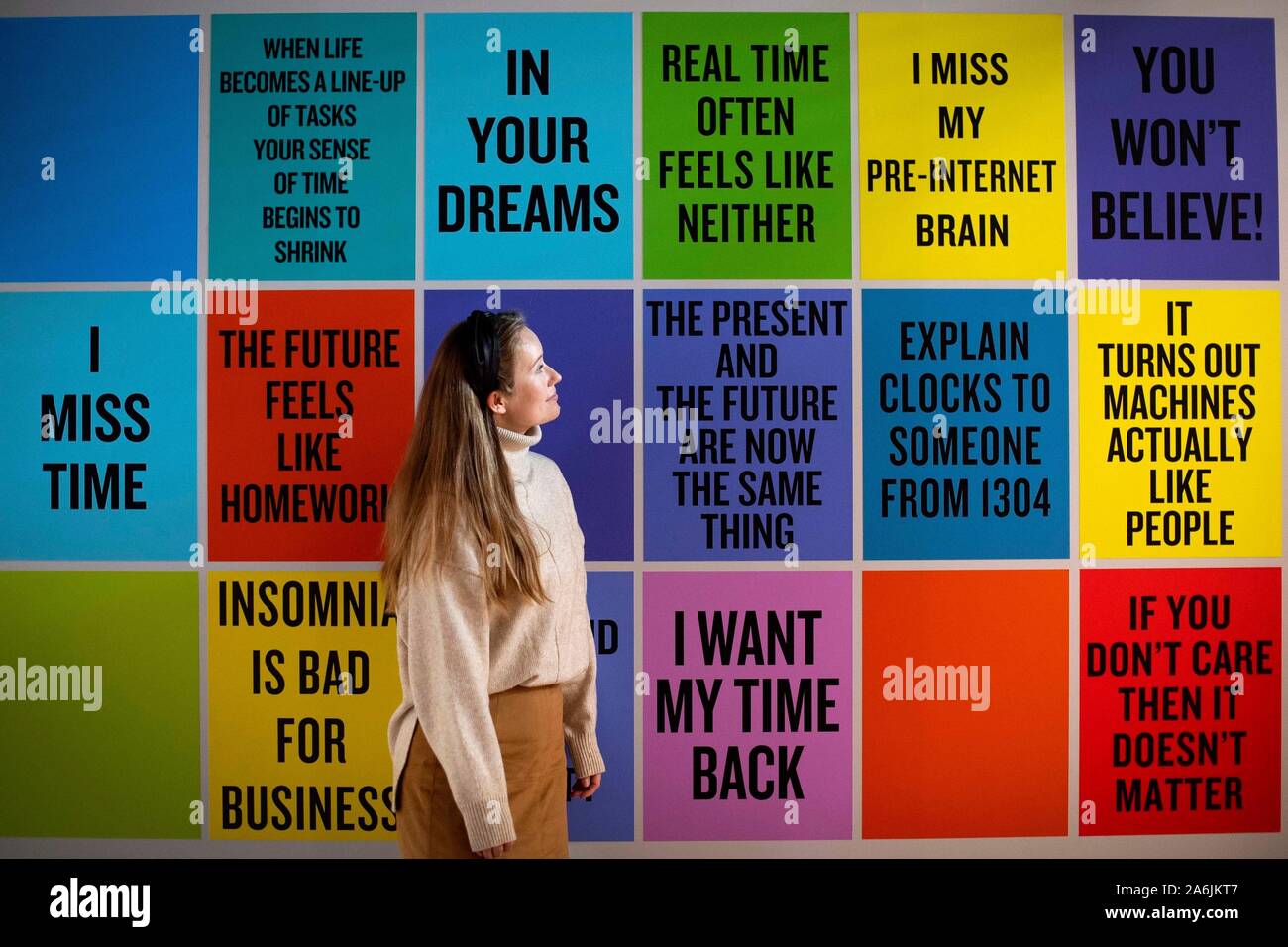 A staff member looks at 'Slogans for the 21st Century, 2011-ongoing' by Douglas Coupland, during the press preview for the winter art exhibition at Somerset House, the Strand, London, entitled 24/7: A Wake-Up Call For Our Non-Stop World. The exhibition shows a series of immersive works, from a global range of artists, examining our inability to switch off from 24/7 culture. Stock Photo
