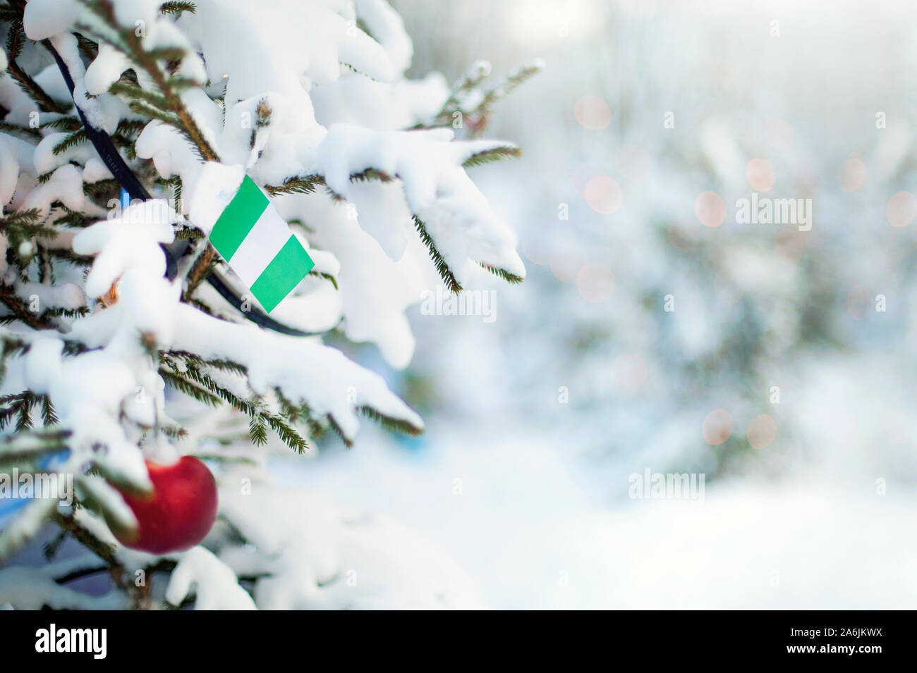 Christmas Nigeria. Xmas tree covered with snow, decorations and a flag