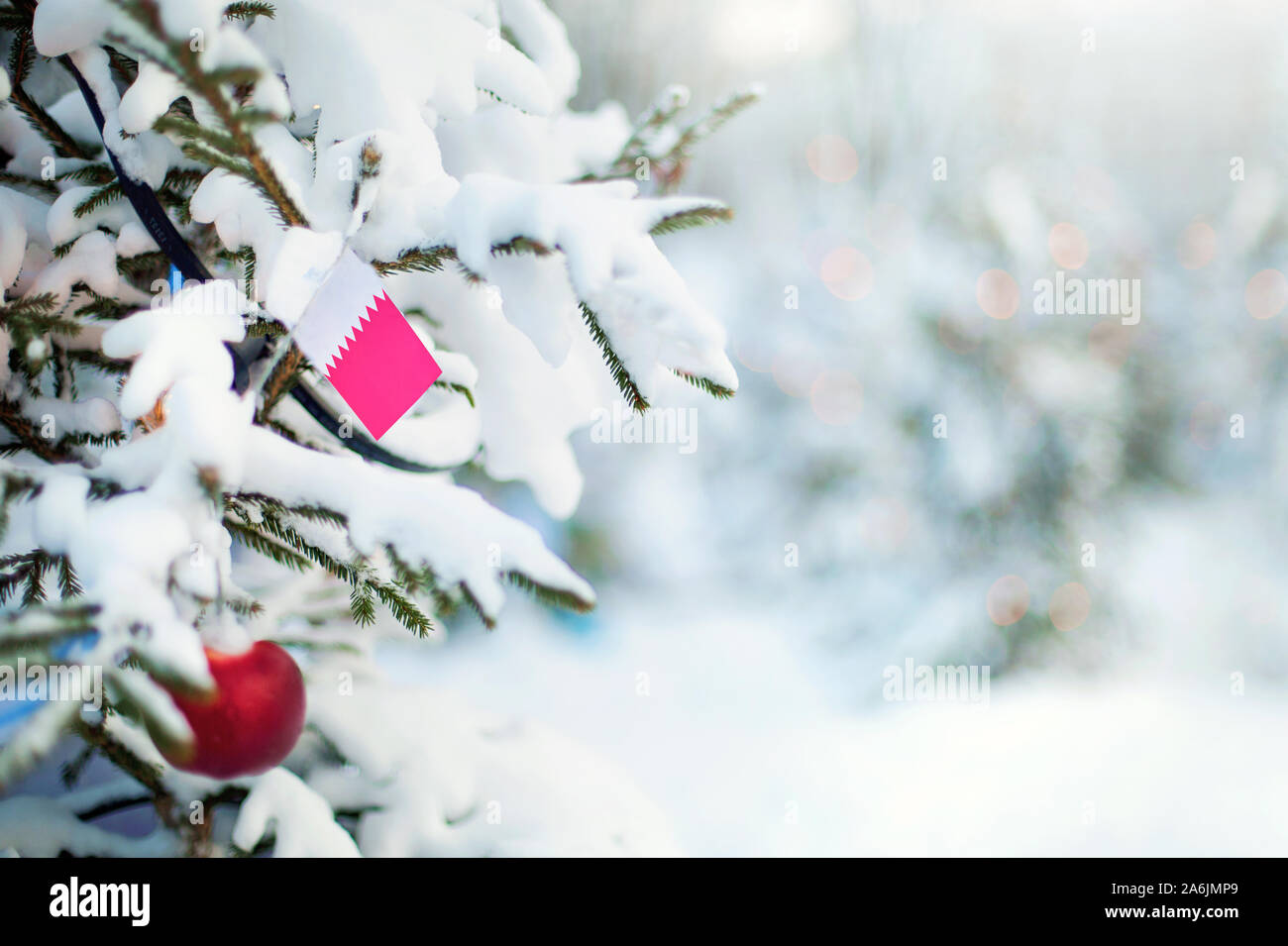 Christmas Qatar. Xmas tree covered with snow, decorations and a flag