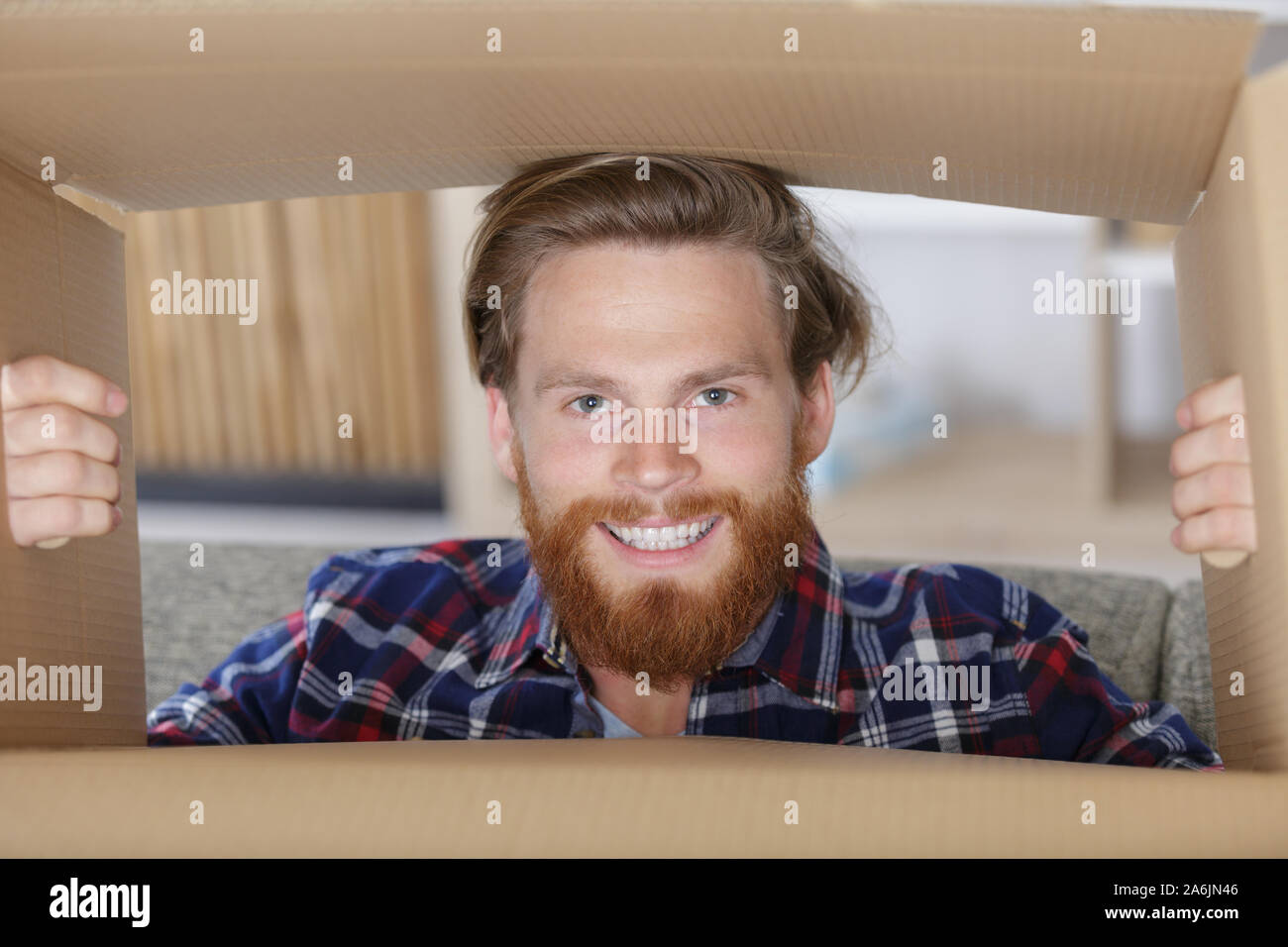 bearded man looking through a cardboard box Stock Photo