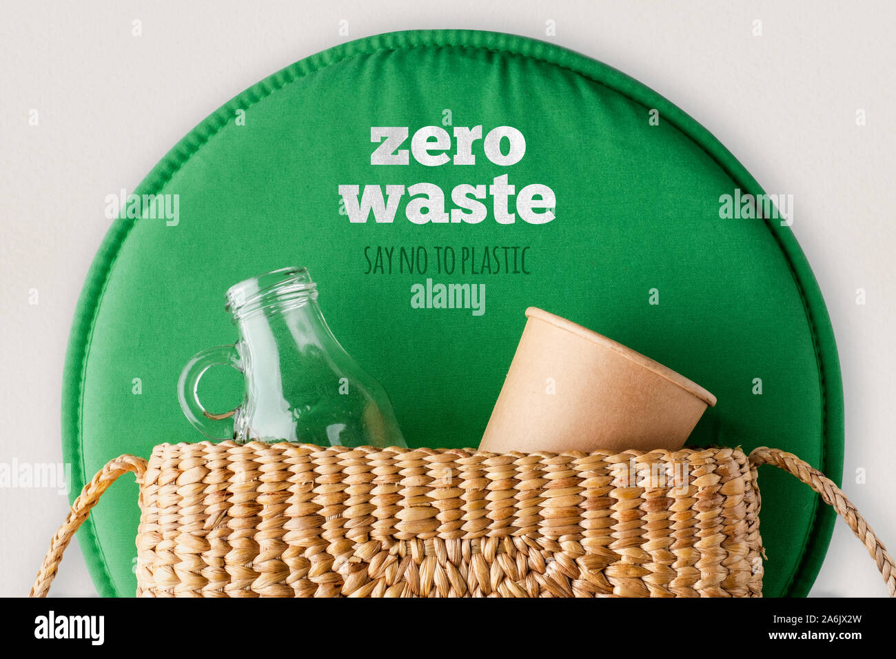 zero waste say no to plastic concept.top view wicker bag with glass bottle and reusable cup with green leaf on white table.eco friendly for environmen Stock Photo