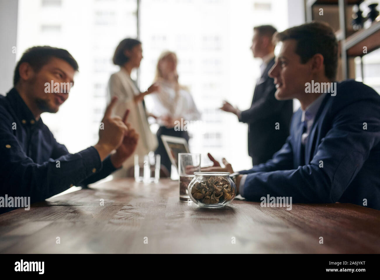 blurred photo of business people having pleasant conversation, three colleagues are talking in the backgroud of the photo. mn teaching new employee, g Stock Photo