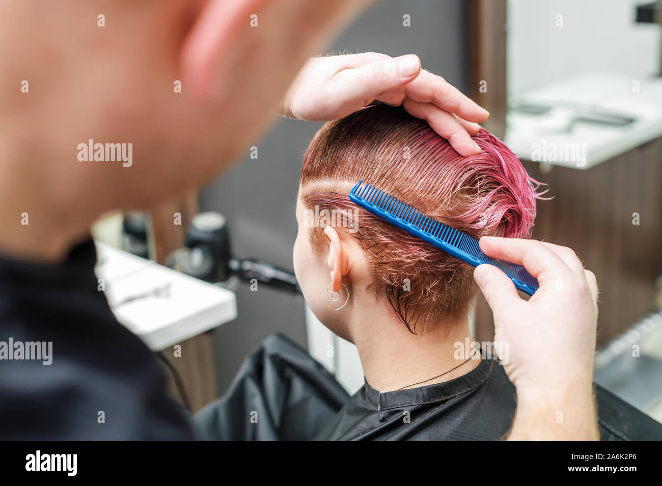 The hairdresser is using comb for female pink hair in hair salon. Male hand  is combing woman short pink hair at beauty salon. Close up Stock Photo -  Alamy