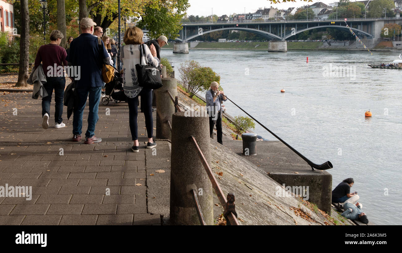 Passerby on the Rhine promenade hear the music of an alphorn musician. Stock Photo