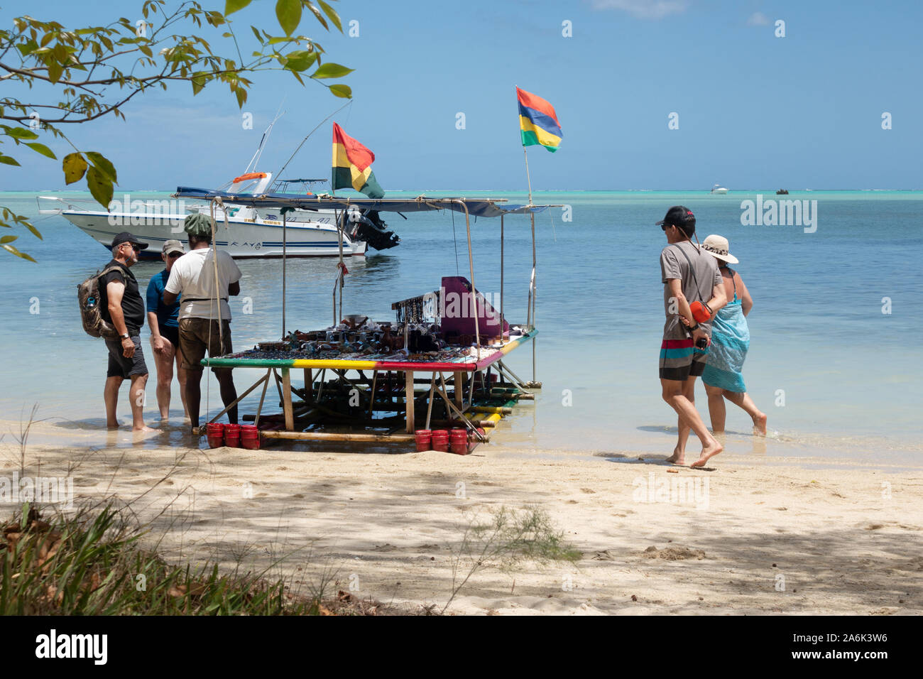 Mauritius tourists; tourists on the beach shopping from a boat stall selling gifts and souvenirs, Ile aux Benitiers, Maurtius Stock Photo