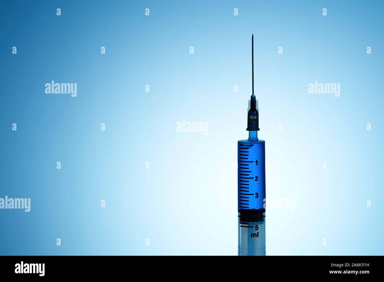 Syringe filled with blue liquid on blue background Stock Photo