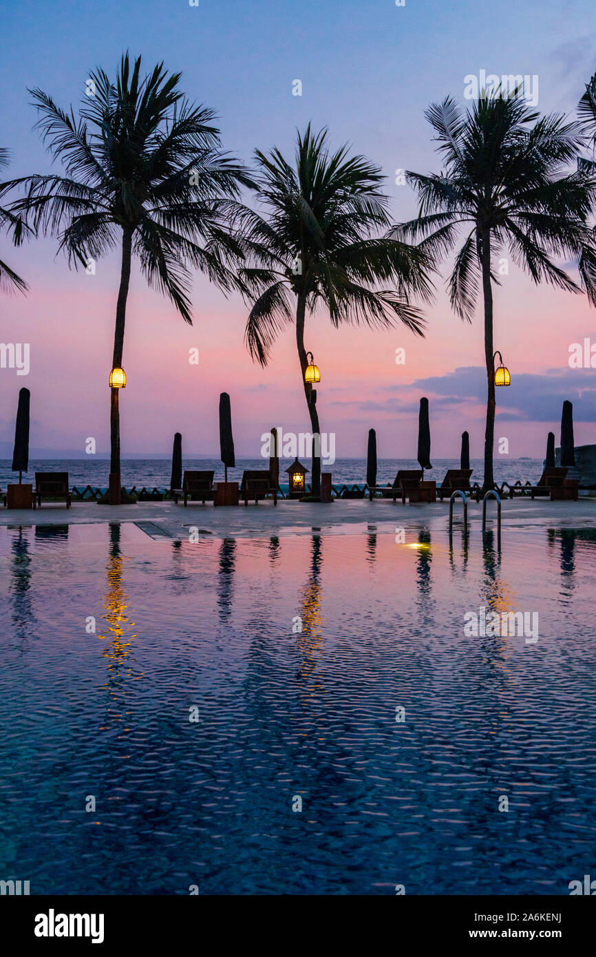 Luxury hotel swimming pool with palm trees and the Indian Ocean at dusk, Candidasa, Eastern Bali, Bali, Indonesia, Southeast Asia, Asia Stock Photo