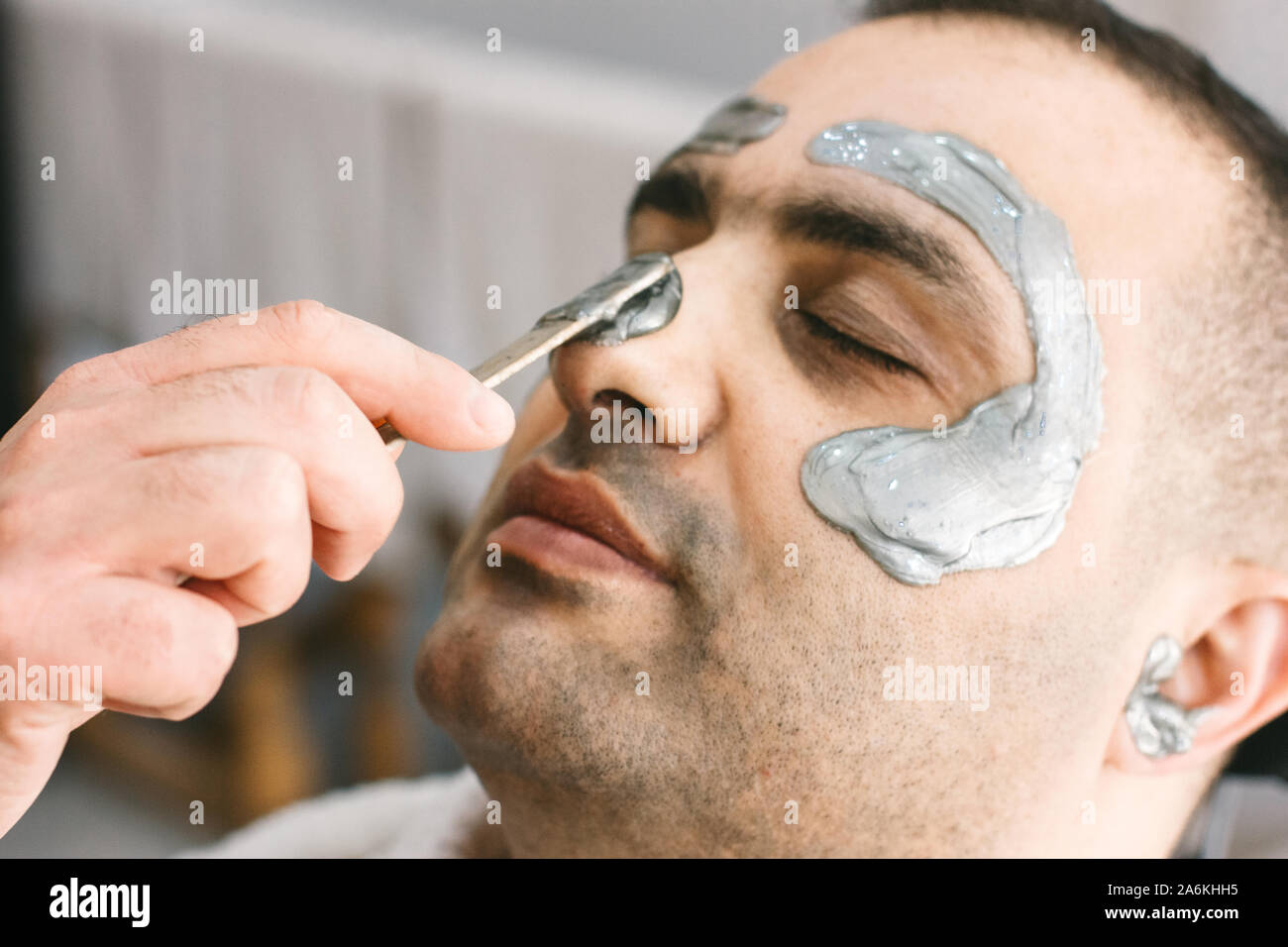 Male face waxing. Barber removes hair by shugaring from face of