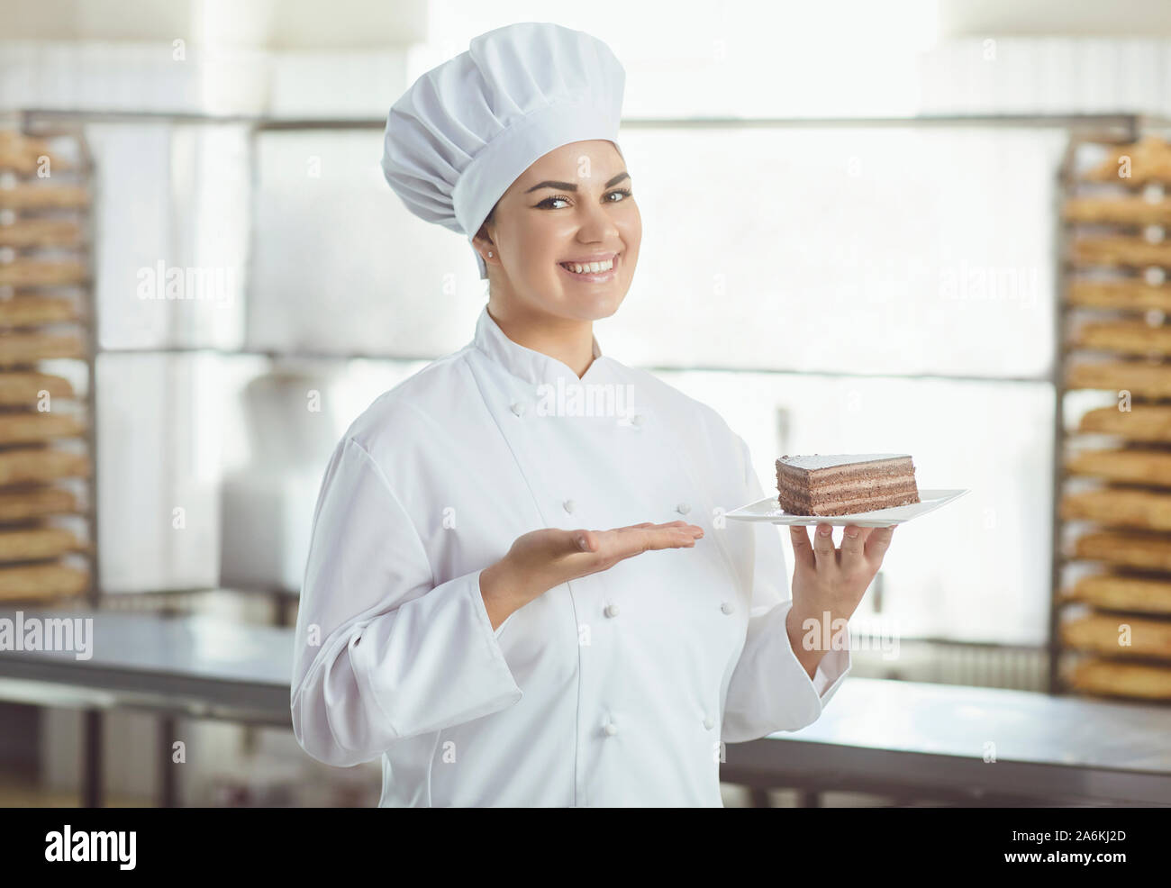 Pastry chef with pastry cake in hands at the bakery. Stock Photo