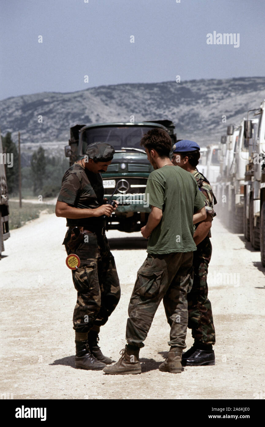 5th July 1993 During the war in Bosnia: HVO (Bosnian Croat) soldiers talk with a British soldier next to a line of British Army Leyland DAF trucks, halted at an HVO checkpoint on Route Circle, just north of Tomislavgrad in western Bosnia. They are on their way to Gornji Vakuf and Vitez. Stock Photo