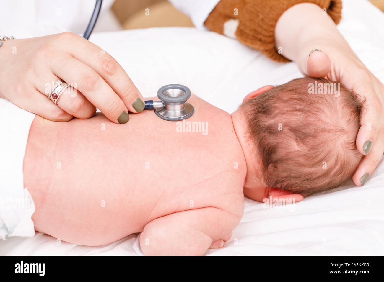 Pediatrician examines two week old baby's back in pediatric clinic